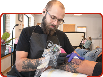 a man tattooing on a person's arm