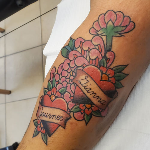 a person's arm with hearts and flowers tattoo